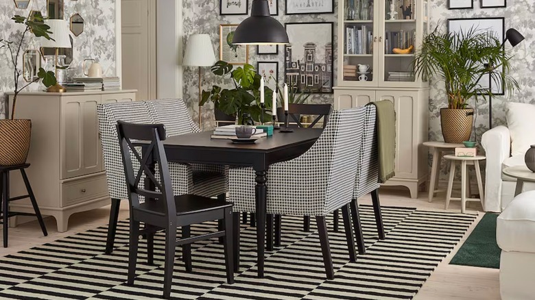 A bold dining room features black and white toile wallpaper, gingham chairs, and a striped STOCKHOLM rug from IKEA
