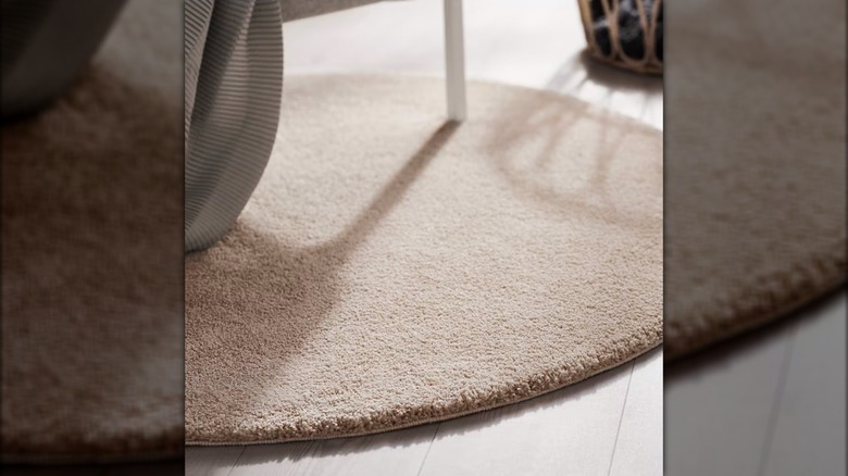 A beige STOENSE Round Rug from IKEA is shown in a detail shot under a white chair leg
