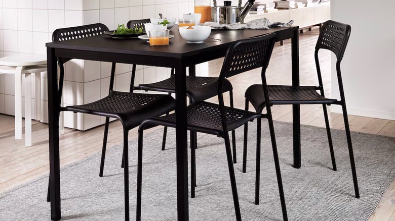 A modern black table sits on an IKEA TIPHEDE rug in black