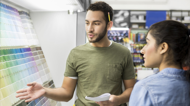 Employee showing customer paint samples in a home improvement store
