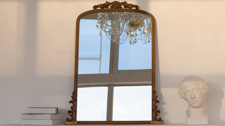 A gold french mirror on a white wall.