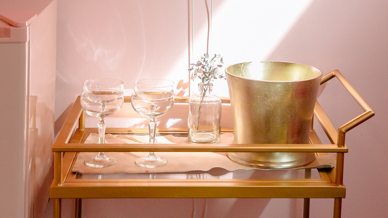 A gold bar cart with champagne glasses.