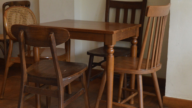 Different vintage chairs around a wood table.