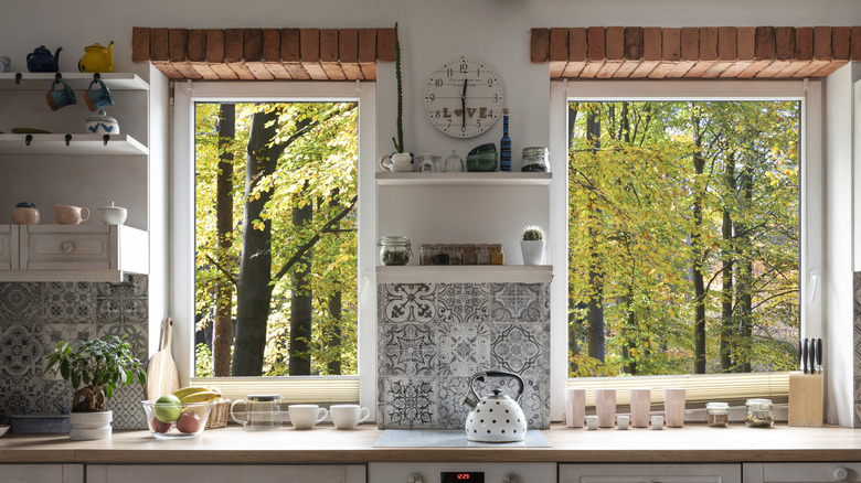 Kitchen with view through window on forest and exposed brick at the top.