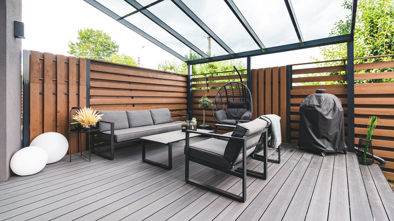 A modern deck with gray furniture and wood walls.