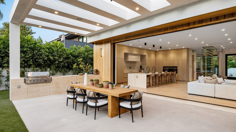 Outdoor kitchen with a built-in grill and countertop against a modern house.