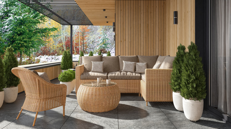 A patio with wicker furniture and wood walls.