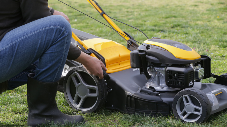 Male hands pulling a lever on a lawn mower to change its settings