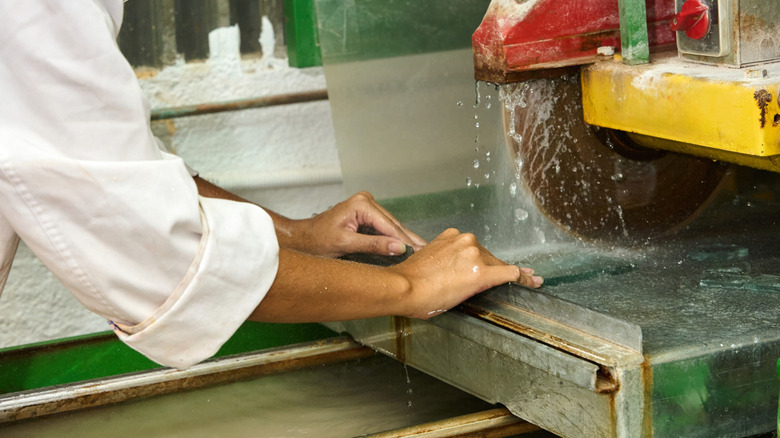 A wet glass tile is being cut with a tile saw