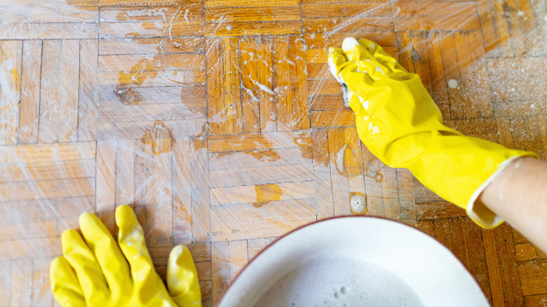 Person scrubbing wooden floor