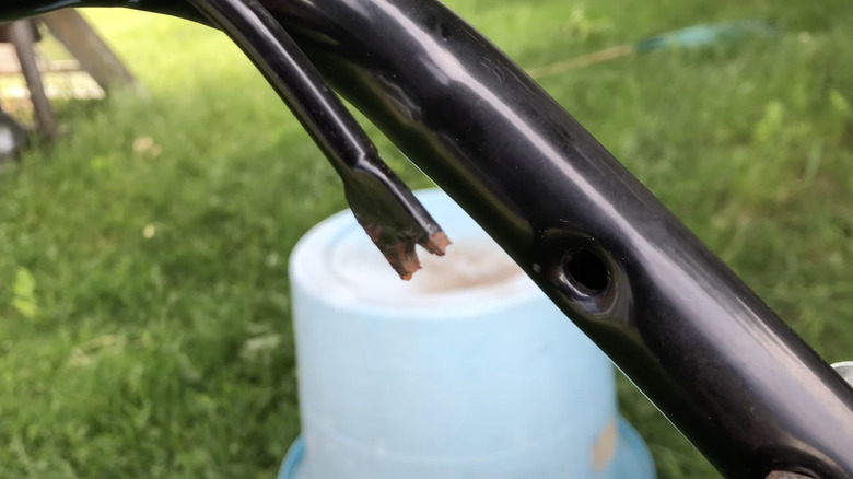 Close up of the broken lawn mower bail bar