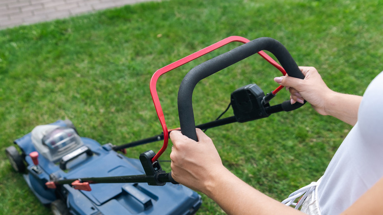 A close up of a lawn mower showing the bail arm safety feature