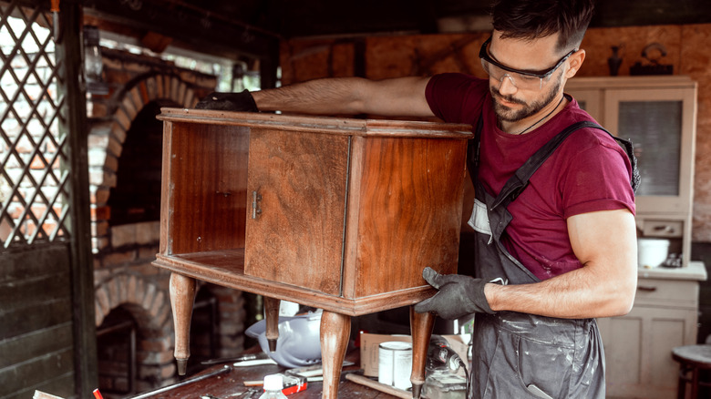 A man carrying a piece of antique furniture