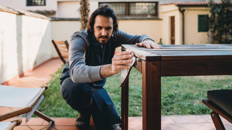 Man sanding a wood table in his yard