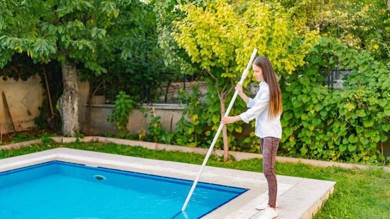 Woman vacuuming the pool 