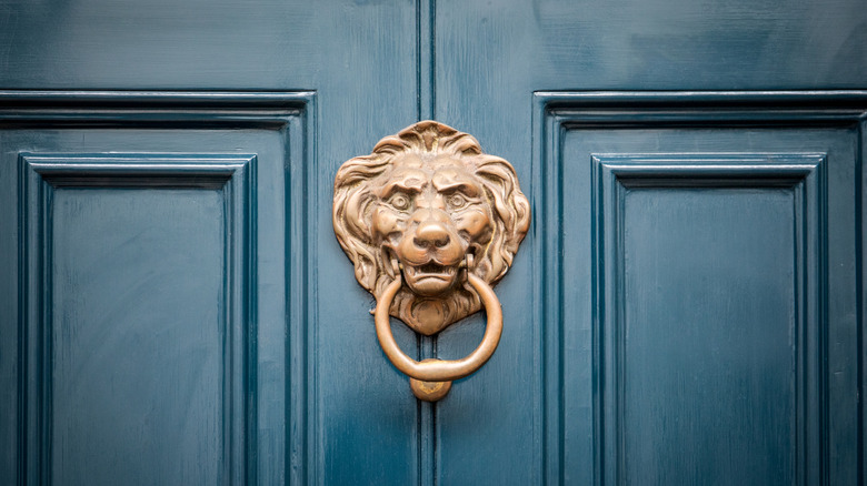 A blue painted door with a bronze lion door knocker.
