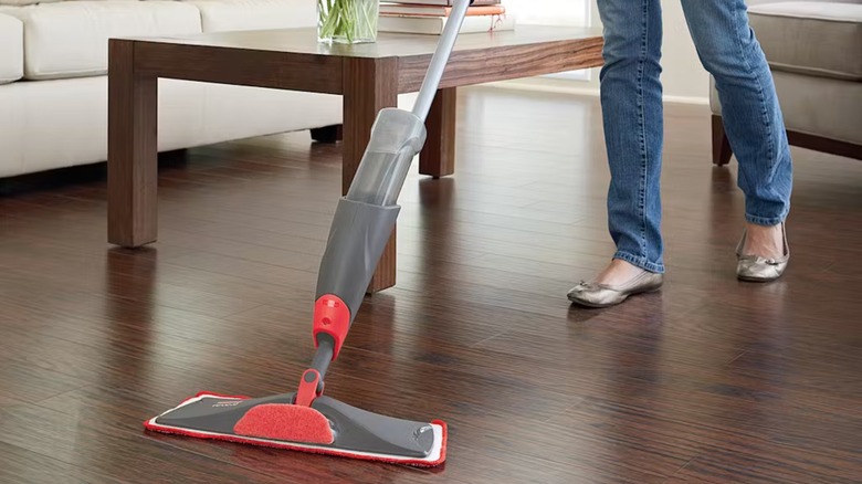 A woman clenaing a wood floor with a Rubbermaid Reveal Spray Mop