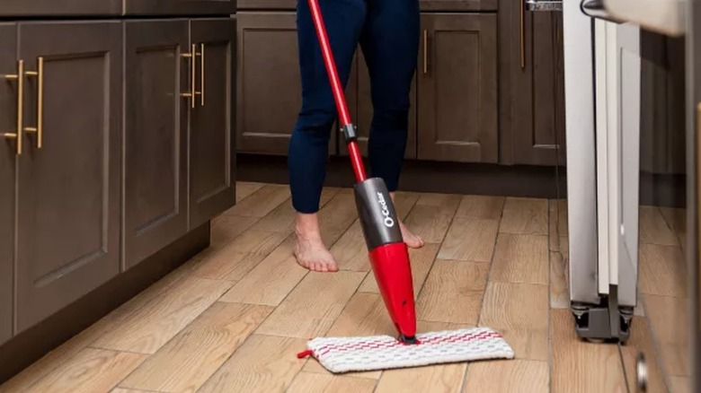 A woman cleaning a wood floor with an O-Cedar spray mop