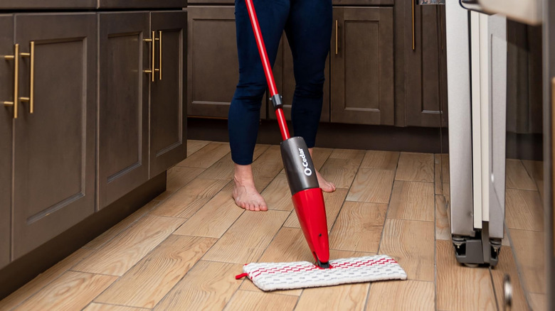 A woman cleaning a wood floor with an O-Cedar spray mop