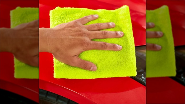 person using yellow microfiber towel on car