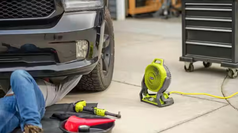 Ryobi portable fan and Bluetooth speaker keeping man comfortable while working on his car