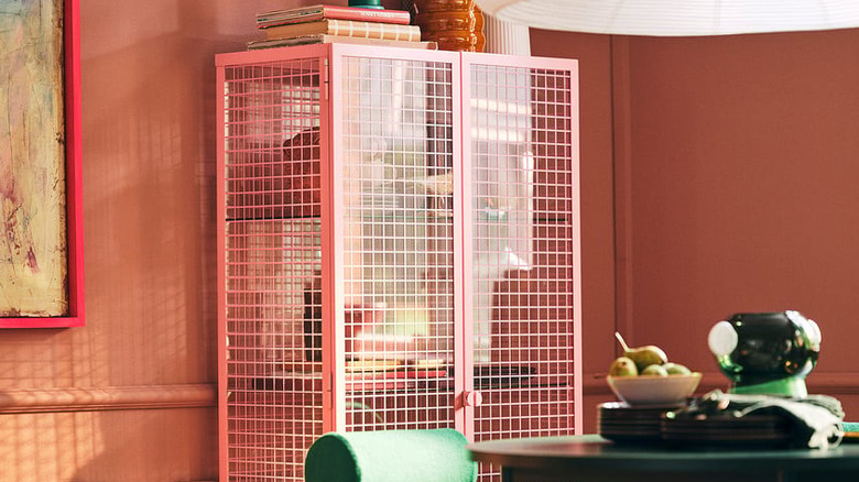 A glass IKEA cabinet with a pink grid pattern holds items in a cozy room.