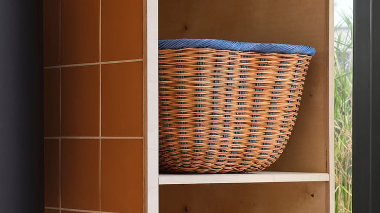 An IKEA rattan basket sits on a shelf in an open cabinet.