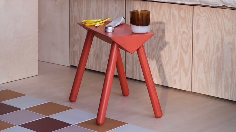 An IKEA stand holds a vase and other objects in a room with warm-toned decor.