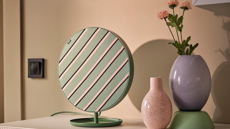 A mint green IKEA speaker sits next to a vase on a dresser.