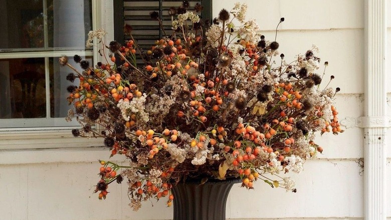 Porch display of large black vase with dried flowers
