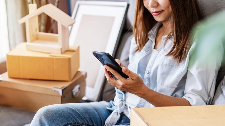 Woman holding phone near boxes