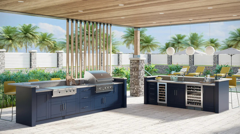 An outdoor kitchen with navy blue cabinets, grill, and wine storage