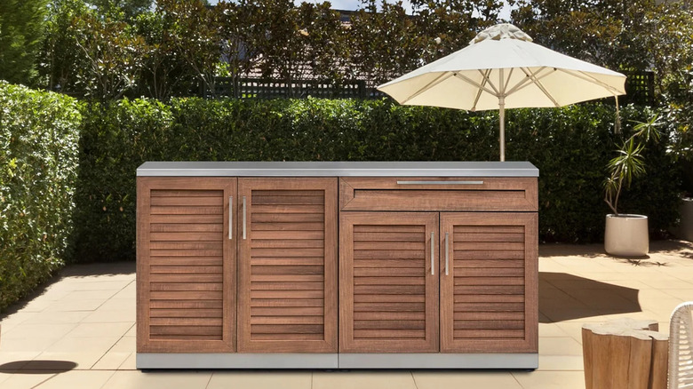 A wood panel outdoor kitchen on a sunny patio.
