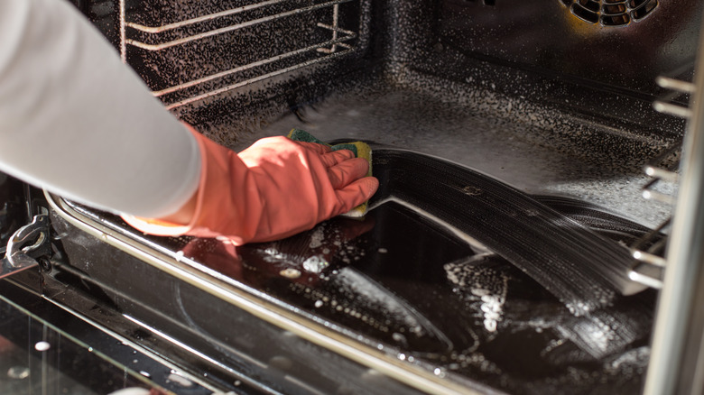 person cleaning oven