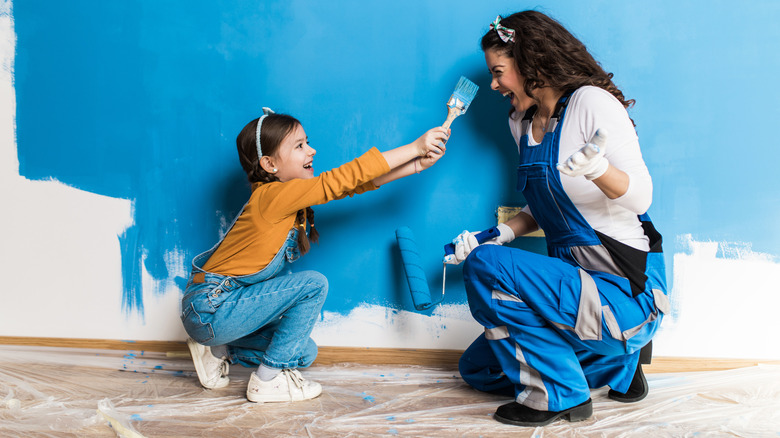 mom and girl painting wall blue