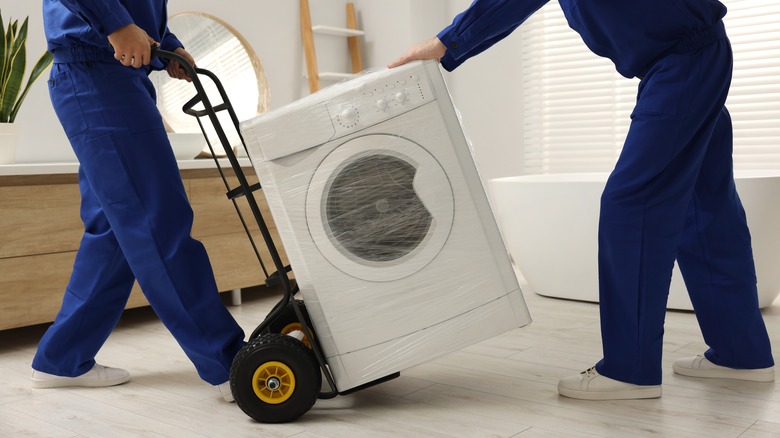 Movers transporting a washing machine on a dolly