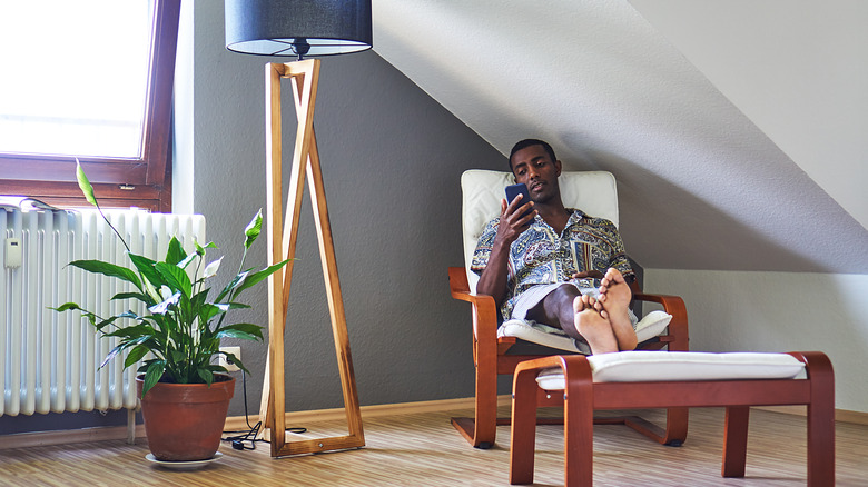 Man relaxes in chair with peace lily beside him