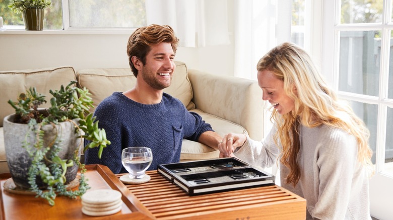 Smiling couple playing backgammon at living room coffee table