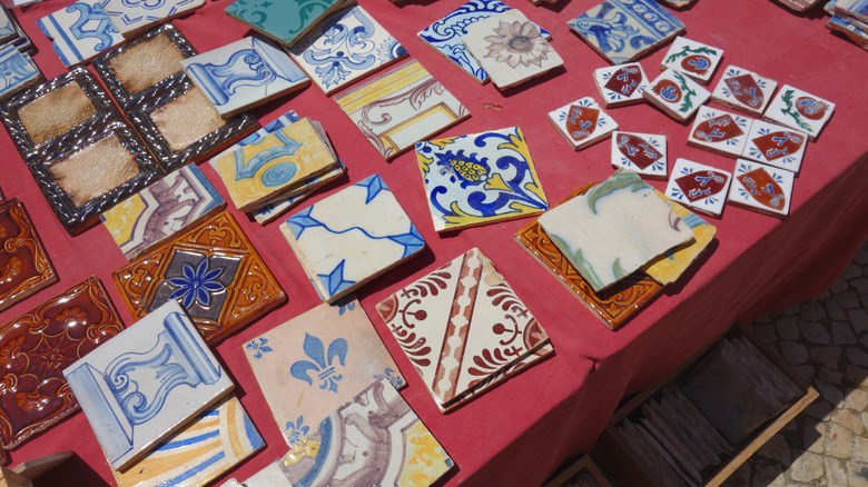A collection of colorful secondhand tiles for sale on a table