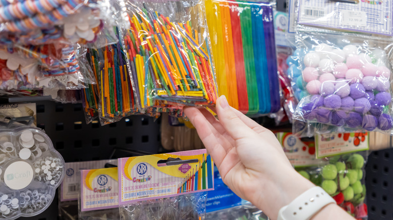 A hand grabs some craft supplies off of a hook in a store