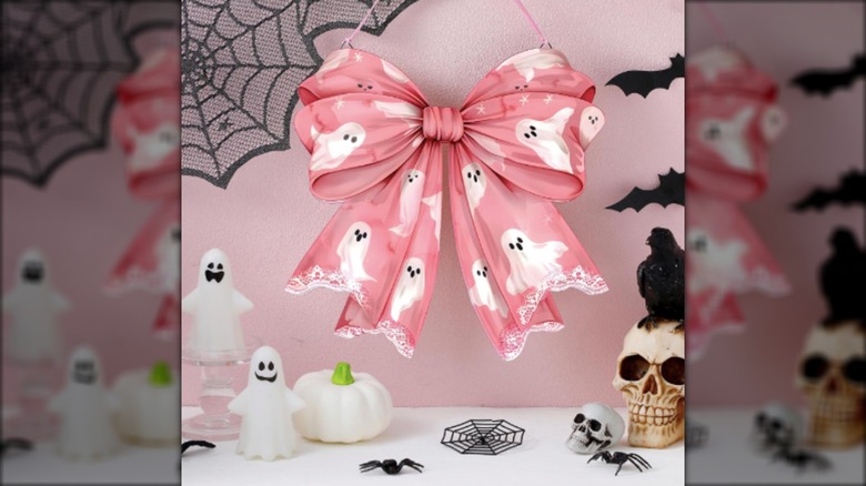 A pink bow covered in ghosts hangs among cute Halloween decor