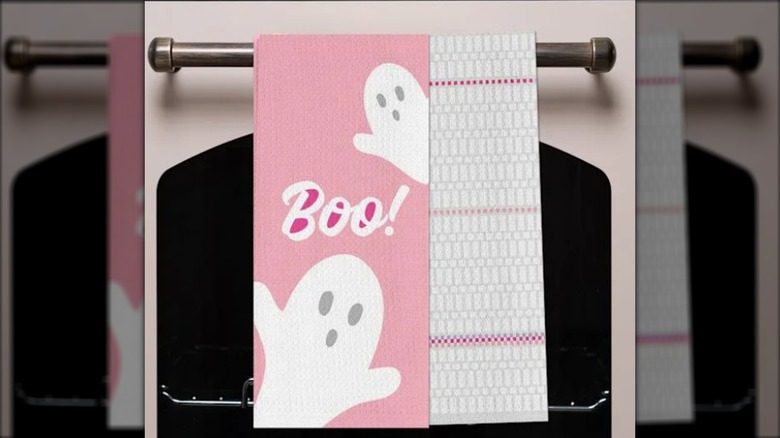 A pink Halloween-themed dish towel hangs on an oven.