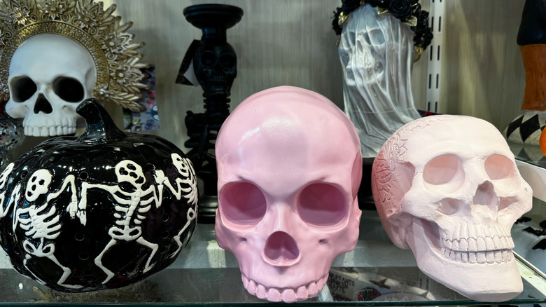 Pink skulls are displayed on a store shelf with other Halloween items