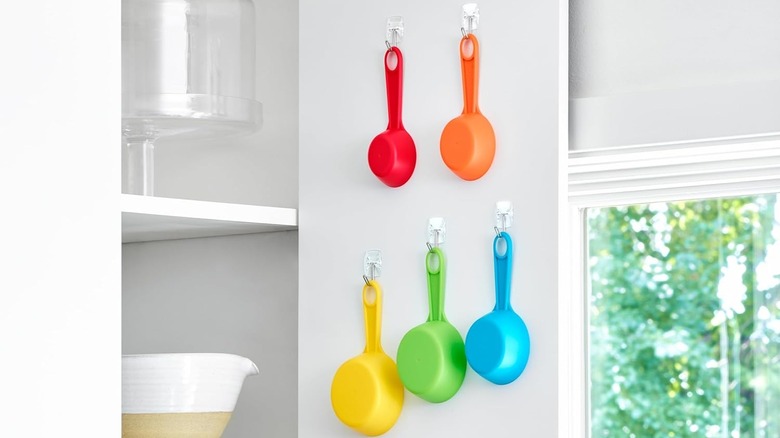Colorful set of measuring cups hung from hooks inside cabinet