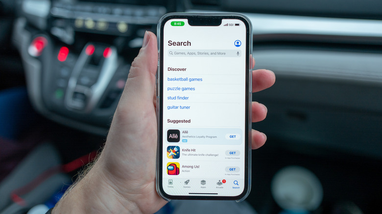 A person holding an iPhone open to the app store