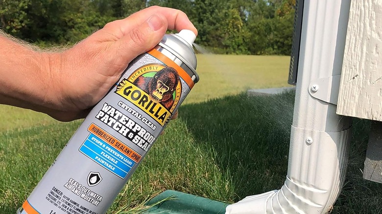 Person using Gorilla waterproof spray on a leaky downspout