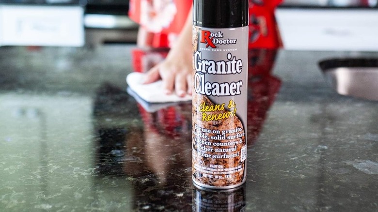 Person cleaning a quartz countertop with a spray-on cleaner