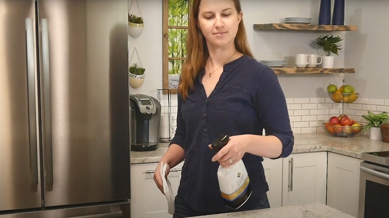 Woman spraying Stone Care International cleaner on a countertop