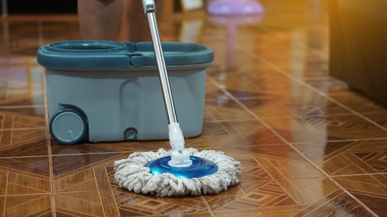 Close up of man using a spin mop to clean the floor.