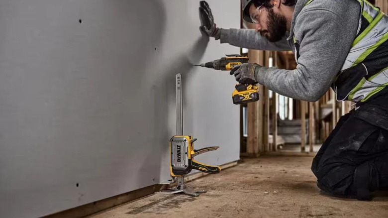 person using DeWalt construction jack for lifting drywall panel